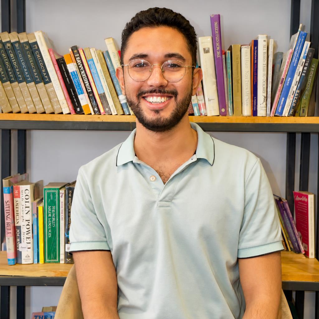 Mathew Benavides sonriendo frente a una biblioteca